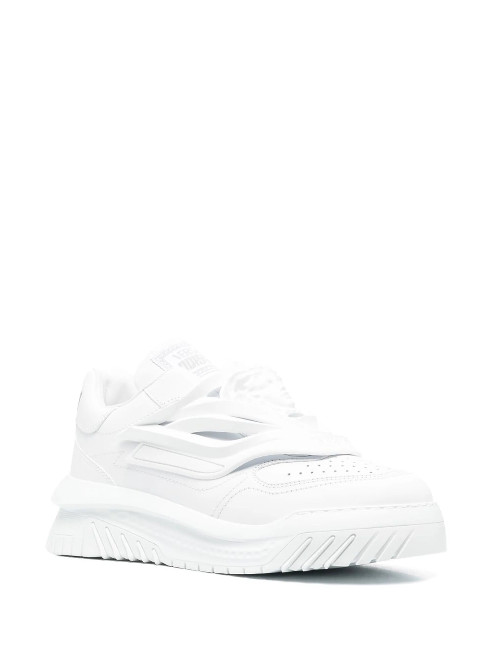 A pair of white low-top Versace Odissea sneakers with a full white color scheme and a logo on the heel.
