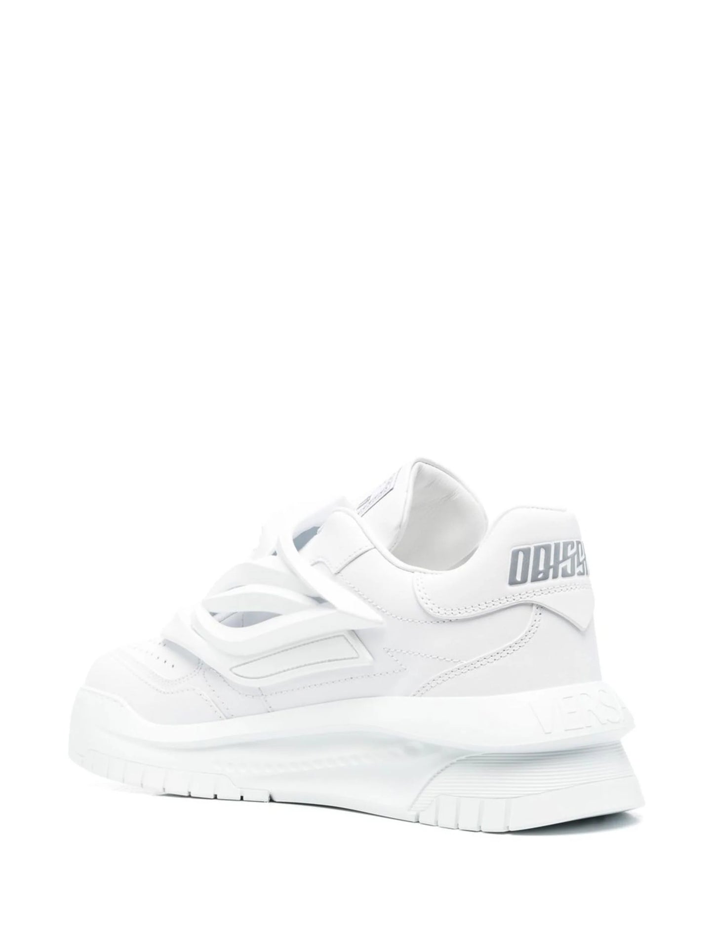A pair of white low-top Versace Odissea sneakers with a full white color scheme and a logo on the heel.