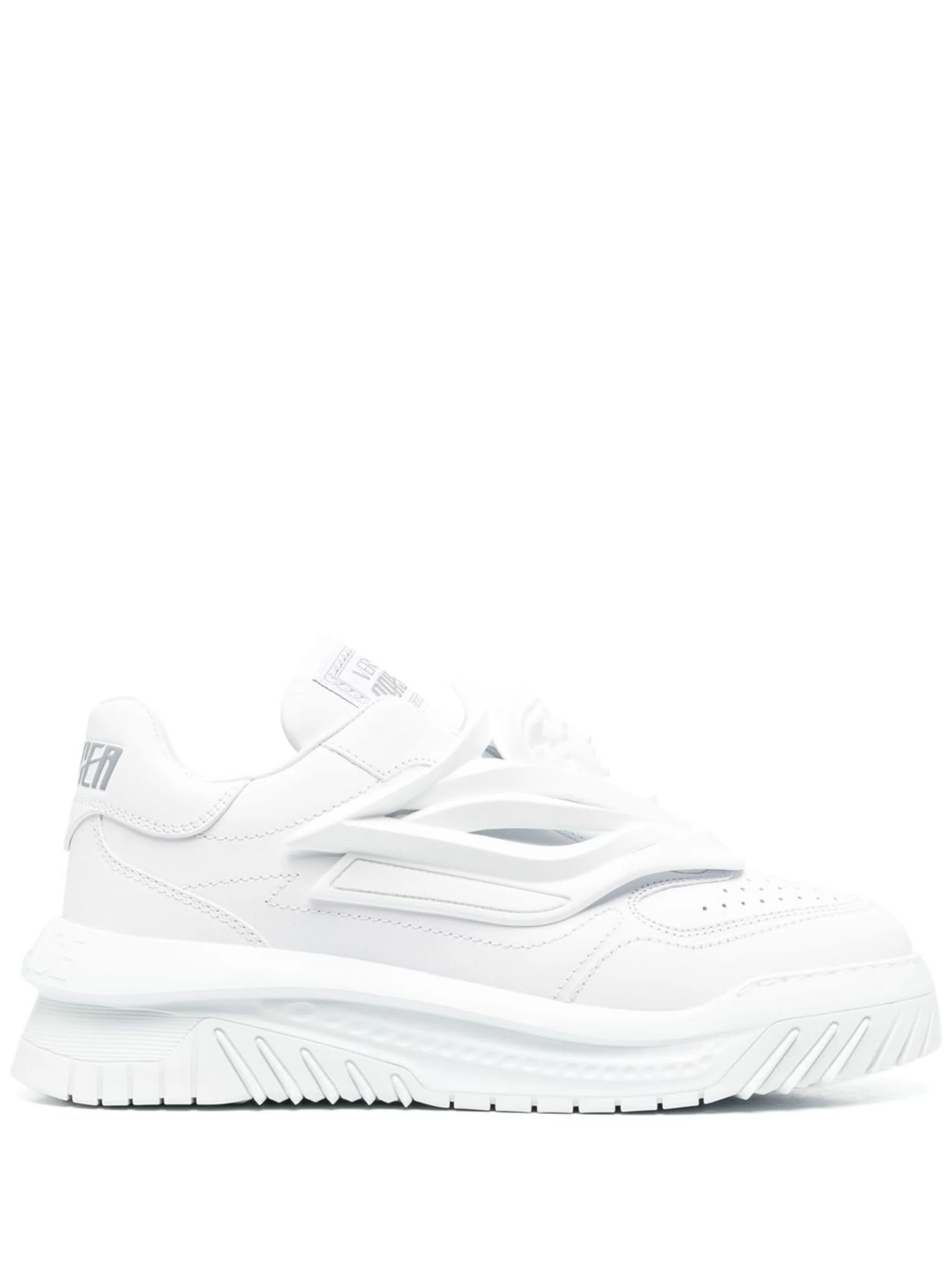 A pair of white low-top Versace Odissea sneakers with a full white color scheme and a logo on the heel.